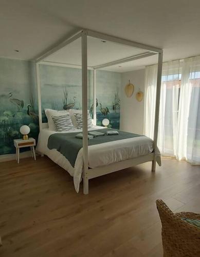 une chambre avec un lit à baldaquin dans une pièce dans l'établissement La Maison Tchanquée jusqu'à 12 personnes Jacuzzi privé, à Gujan-Mestras