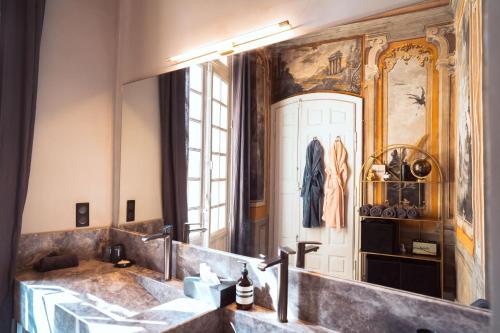 une salle de bain avec un lavabo et un grand miroir dans l'établissement Hôtel particulier 123m² centre historique Avignon., à Avignon