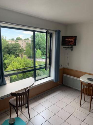 a room with a table and a large window at Studio Bourran + parking in Rodez