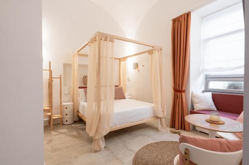 1 dormitorio con cama con dosel y sofá en Maison Le Graziose en Sant'Agnello