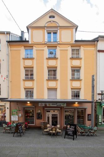 a building with tables and chairs in front of it at Haus Moselwelt Anton in Zell an der Mosel