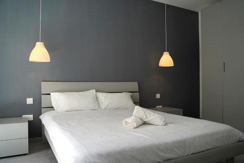 een slaapkamer met een wit bed en 2 hanglampen bij lovely apartment close to the sea in Il-Gżira