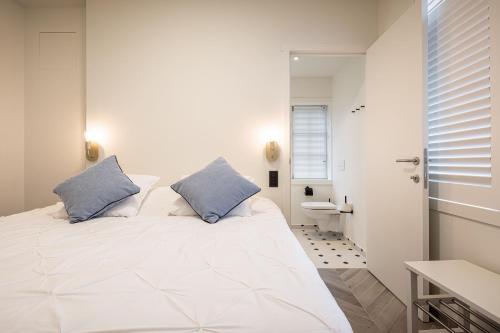 a bedroom with a large white bed with blue pillows at Villa Zomerrust in De Panne