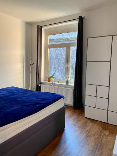 sypialnia z niebieskim łóżkiem i oknem w obiekcie Entspannt Mittendrin w Hanowerze