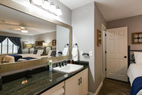 a bathroom with a sink and a bed and a mirror at 2BR Penthouse Condo - Near The Strip - Free WIFI - Pool - FREE TICKETS INCLUDED - CLC-12 in Branson