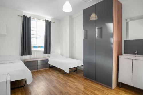 a room with two beds and a tv at Halpin House (South Kensington) in London