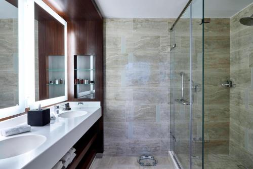 a bathroom with two sinks and a glass shower at Marriott Santa Cruz de la Sierra Hotel in Santa Cruz de la Sierra