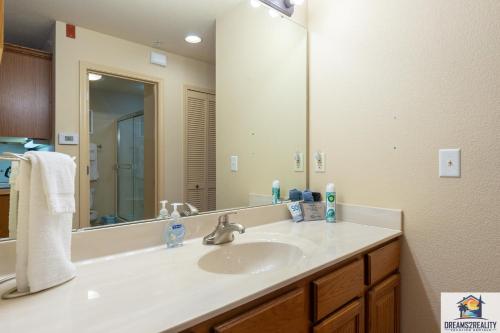 a bathroom with a sink and a large mirror at 1BD King Condo with 2 Person Jacuzzi Tub - Near The Strip - FREE TICKETS INCLUDED - T1-9 in Branson