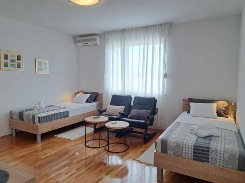 a small bedroom with two beds and a chair at Apartman dida Jakov in Primošten