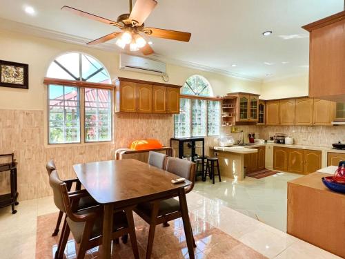 a kitchen with a wooden table and a ceiling fan at My Excel Garden Deluxe Villa with Orchard and Pool in Air Hangat