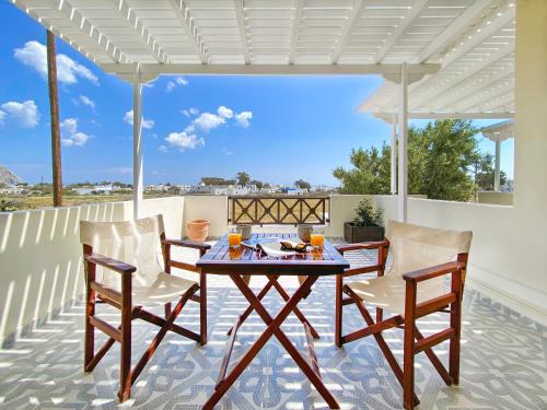 un patio con mesa y sillas bajo una pérgola blanca en Almyra Villa, en Perissa