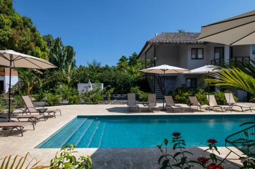 a swimming pool with chairs and umbrellas next to a house at Yuli Hotel in Uvita