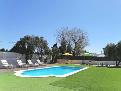 a swimming pool with chairs and a table and chairs at Quinta da Torre in Torre