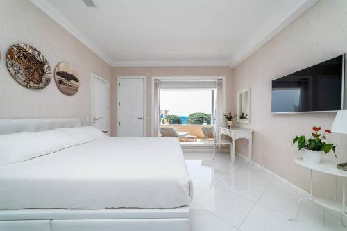 a white bedroom with a large bed and a television at Casa Nua in Puerto del Carmen