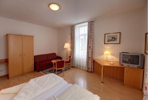 a bedroom with a bed and a desk and a tv at Postwirt in Seeboden