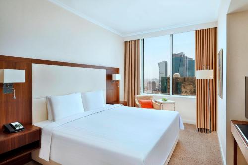 a bedroom with a white bed and a large window at Courtyard by Marriott Riyadh Olaya in Riyadh