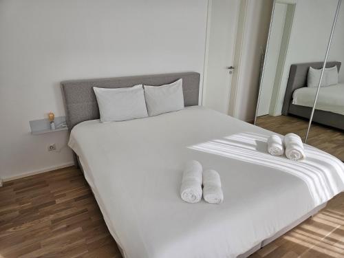 Una cama blanca con dos pares de zapatillas. en New Spacious Two Bedroom Center with Parking, near Public Transport, en Luxemburgo