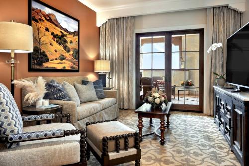 a living room with a couch and a tv at Inn at the Mission San Juan Capistrano, Autograph Collection in San Juan Capistrano