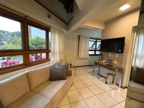 a living room with a couch and a flat screen tv at Pousada Villa Verde in Canela