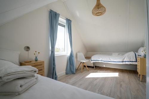 シント・マールテンにあるMeertje Villa 81 op Recreatiepark De Wielenのベッドルーム1室(ベッド1台、青いカーテン付きの窓付)