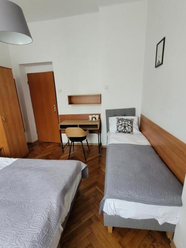 a room with two beds and a table and a desk at Zajazd Meran in Krynica Zdrój