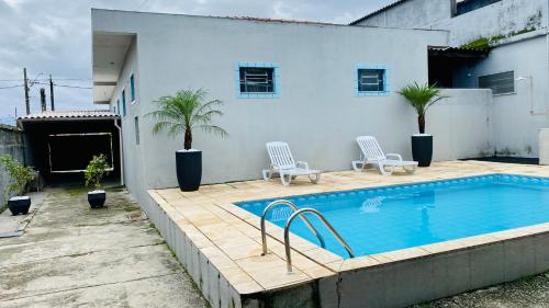 einen Pool mit zwei Stühlen neben einem Gebäude in der Unterkunft Casa Pôr do Sol in Itanhaém