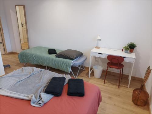 Cette chambre comprend deux lits, un bureau et une table. dans l'établissement Sweet Home, à Mulhouse