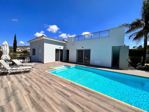 a villa with a swimming pool in front of a house at New Heaven in Sea Caves in Peyia