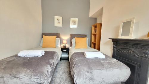 two twin beds in a room with a fireplace at Colenso St - 2 bed house by Bishy Road & River in York