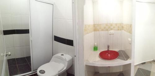 a bathroom with a toilet and a red sink at HOSTAL LA MACARENA in El Zaino