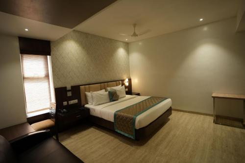 a hotel room with a bed and a window at Sri Ambal Grand in Virudunagar