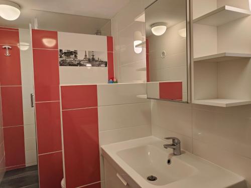 La salle de bains est pourvue d'un lavabo et d'un mur rouge. dans l'établissement Etoile de Mer - Appt 3 ch 2 sdb à 150m d'une plage de sable fin hyper équipé & Wifi, à Saint-Mandrier-sur-Mer