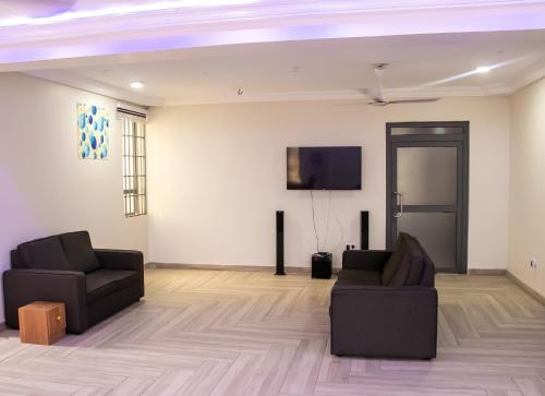 un soggiorno con 2 sedie e una TV a schermo piatto di THE GRANGE HOTEL GHANA a Dawhwenya