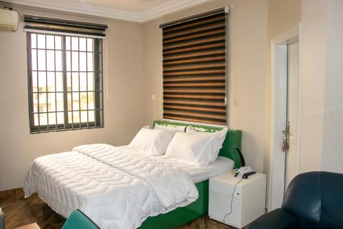 a bedroom with a large bed with white sheets at THE GRANGE HOTEL GHANA in Dawhwenya