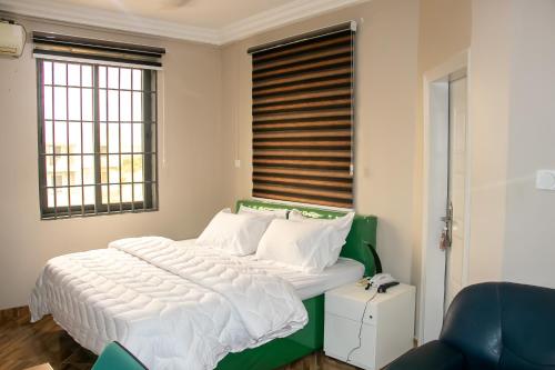 a bedroom with a large bed with a green headboard at THE GRANGE HOTEL GHANA in Dawhwenya