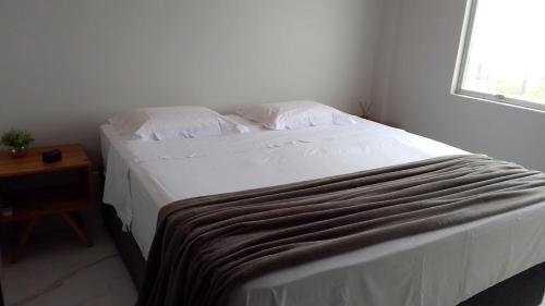 a bedroom with a large white bed with a window at Apartamento Excelente Pé na Areia in Guaratuba