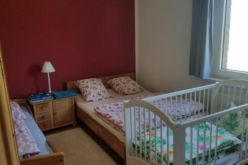 a bedroom with a crib and a bed and a window at Ferienwohnung Alte-Schule-Kail Wohnung 2 in Kail
