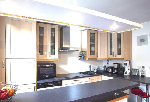 a kitchen with wooden cabinets and a black counter top at Villa Manarola - 10pers/4Ch - jacuzzi & jardin in Longjumeau