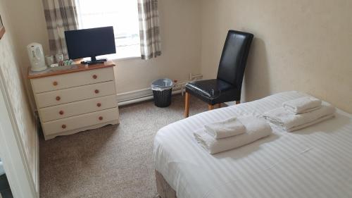 a bedroom with a bed and a chair and a television at HOTEL242 in Blackpool