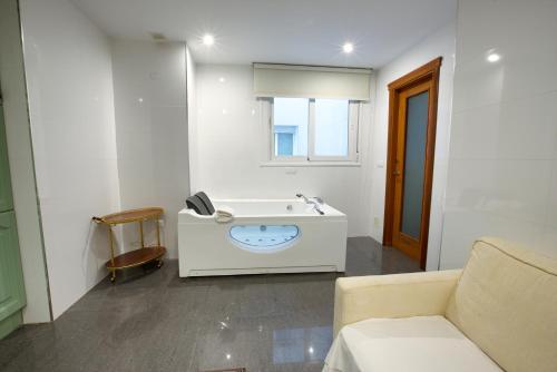 baño blanco con lavabo y sofá en Apartamentos Chvictoria, en Cuenca