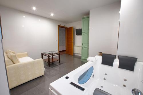a bathroom with a bath tub and a couch at Apartamentos Chvictoria in Cuenca