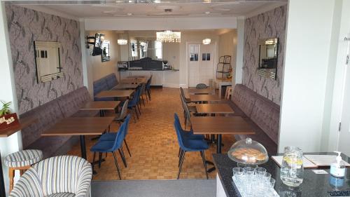uma sala de jantar com mesas de madeira e cadeiras azuis em HOTEL242 em Blackpool