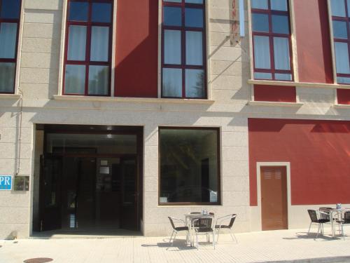 a group of tables and chairs in front of a building at Pensión Residencial Platas in O Pedrouzo