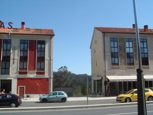 a city street with cars parked in front of a building at Pensión Residencial Platas in O Pedrouzo