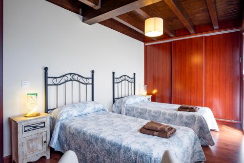 1 dormitorio con 2 camas y pared de madera en Vivienda Vacacional La Prida, en Cangas de Onís