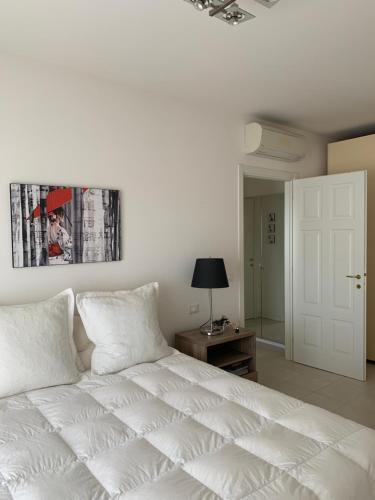 - un lit blanc dans une chambre avec une photo sur le mur dans l'établissement Poetto Apartment, à Quartu SantʼElena