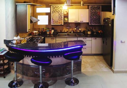 a kitchen with a bar with purple stools at Royal Palace apartment 5 Stars in Cairo