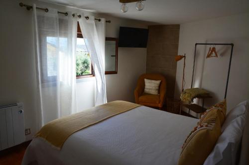 a bedroom with a bed and a window and a chair at Casa do Alfaiate in Chãos