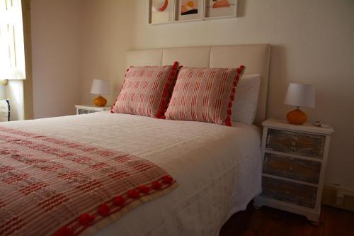 a bedroom with a bed with a red and white comforter at Casa do Alfaiate in Chãos