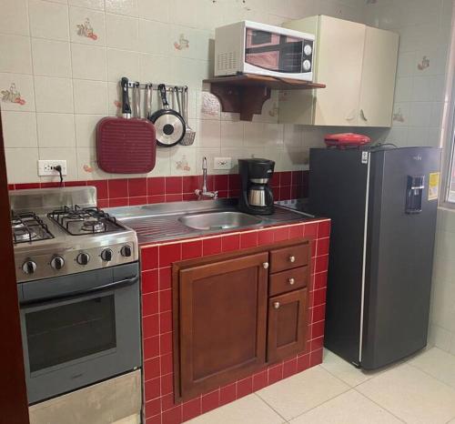 a kitchen with a stove and a sink and a refrigerator at Casa 1090 ubicada cerca a todo. in Leticia